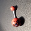 Piercing nombril rouge et noir motif : tête de mort